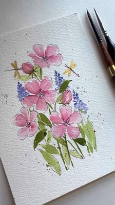 a watercolor painting of pink flowers and dragonflies on white paper with paintbrushes next to it