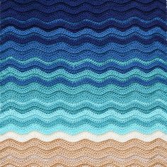 a crocheted blanket with waves in blue, brown and tan colors on it