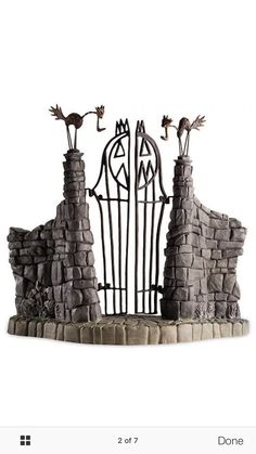 an iron gate with two cats on top and one cat standing at the entrance to it