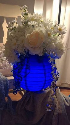 a blue vase filled with white flowers on top of a table