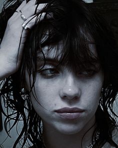 a close up of a person holding their hair in front of her face and looking at the camera