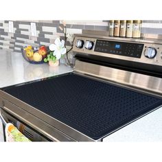 a stainless steel stove top oven sitting in a kitchen next to a bowl of fruit