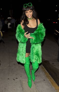 a woman in green fur coat walking down the street