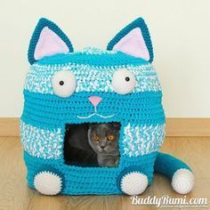 there is a crocheted cat in a knitted blue bag on the floor