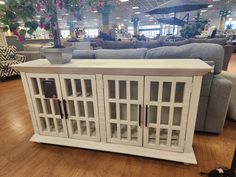 a white cabinet sitting on top of a hard wood floor in a room filled with furniture