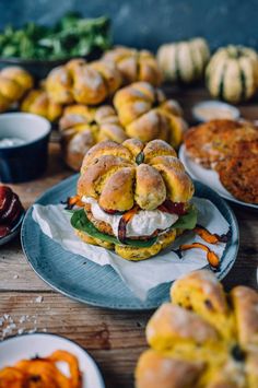 a table topped with plates filled with sandwiches and buns covered in cream cheese on top of them