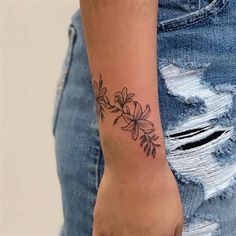 a woman's arm with a flower tattoo on the left side of her wrist