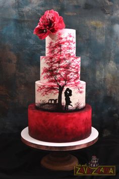 a three tiered cake with red and white frosting on the top, decorated with a silhouette of a man and woman under a tree