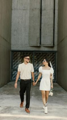 a man and woman holding hands while walking