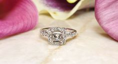 a diamond ring sitting on top of a pink flower