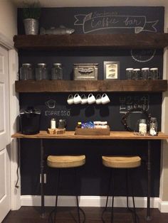 two wooden stools sitting in front of a bar with chalk writing on the wall