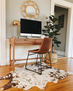 a desk with a computer on it and a cow hide rug in front of it