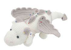 a crocheted white and gray dragon toy laying on top of it's back