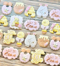 baby shower cookies are arranged on a wooden table with pink and yellow ones in the shape of teddy bears