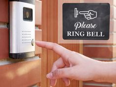 a hand pointing at a ring bell on a brick wall next to a sign that says please ring bell