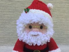 a knitted santa clause doll with glasses and a red hat sitting on a table