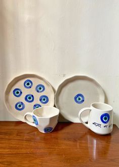 a table topped with plates and cups on top of a wooden table next to a wall