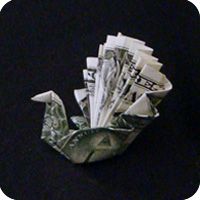 an origami bird made out of money sitting on top of a black surface