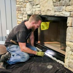 a man in black shirt and gloves working on a fireplace