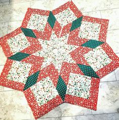 two red and white quilts on the floor with one green patchwork piece in the middle