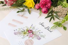 wedding stationery with flowers and greenery laid out on a white tablecloth for guests to sign