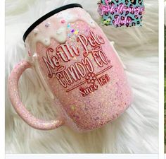 a pink coffee mug sitting on top of a white fur covered floor