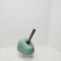 a green toothbrush sitting on top of a plastic holder in a white walled room