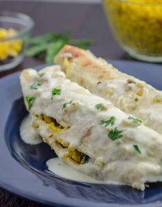 two burritos on a blue plate with yellow corn and green garnish