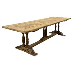 an old wooden table with four legs and two leaves on the base, against a white background