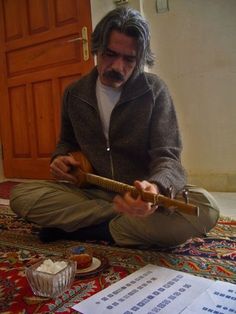 a man sitting on the floor playing an instrument