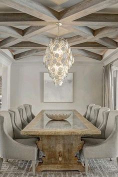 a dining room table with chairs and a chandelier hanging from it's ceiling