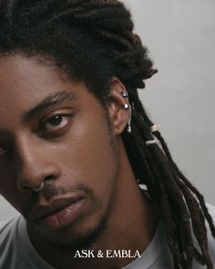 a young man with dreadlocks and piercings on his ear looking at the camera