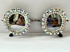 ✨Sparkly round sunglasses. ✨Prepare to dazzle people everywhere you go in these sparkly round sunglasses. These would be great for a special event such as weddings, birthdays, holidays or everyday wear if you love to sparkle 💫 ✨The frames are silver metal and they have silver mirrored lenses. All around the rims they have lots of ab rhinestones with a row of ivory pearls on the inside.  ✨All my glasses come in a black pouch to keep them safe, please also handle with care. ✨Checkout the full collection of Sunglasses here :  https://www.etsy.com/uk/shop/AlexisExclusive?ref=s2-header-shopname ✨To be kept up to date with new designs please FAVOURITE MY SHOP. ✨Find us on Instagram: https://www.instagram.com/AlexisExclusive (Colours may vary slightly due to different screens and monitors) Bride Sunglasses, Yeri Mua, Embellished Sunglasses, Sewing Designs, Black Pouch, Bling Crafts, Rhinestone Sunglasses, Christmas Stocking Pattern, Costume Inspo