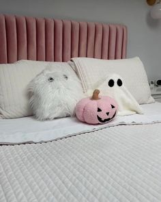 two stuffed animals sitting on top of a bed next to pillows and pillowcases