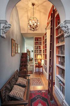 an arched doorway leads to a library with many bookshelves and lamps on either side