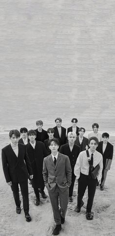 a group of men standing next to each other on top of a sandy beach near the ocean