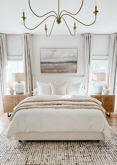 a large white bed sitting in a bedroom next to two windows