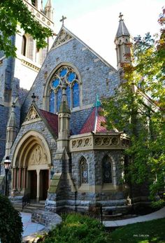 an old stone church with stained glass windows and steeple on the front door is surrounded by greenery