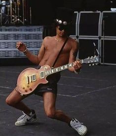 a man with no shirt playing guitar on stage