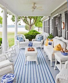 a porch with white wicker furniture and blue and white striped rug on the floor