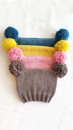 a knitted hat with pom - poms on it