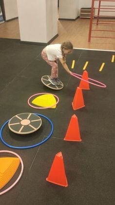 a little boy is playing with some toys on the floor in an indoor gym area