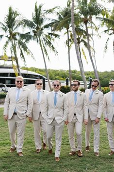 a group of men in suits and sunglasses standing next to each other on the grass