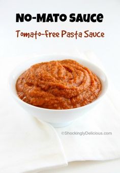 a white bowl filled with tomato sauce on top of a table