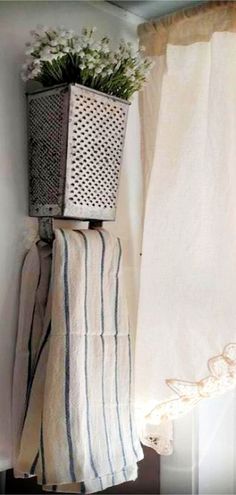 a basket with flowers sitting on top of a shelf next to a curtain and window