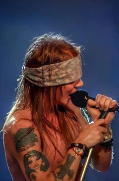 a man with long hair holding a microphone and wearing a blindfold on his head