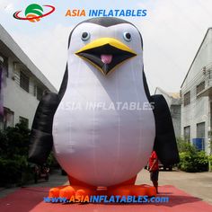 an inflatable penguin standing on top of a red carpet next to a building