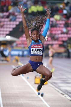 a woman jumping in the air on top of a track