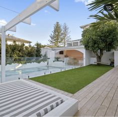 an outdoor patio with grass and trees next to a swimming pool in the back yard