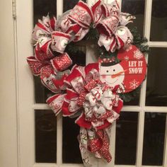 a red and white christmas wreath with snowman decorations on the front door, next to a window